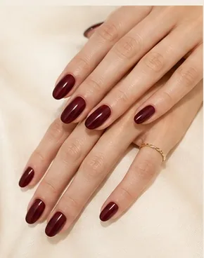 Hands folded on fabric, showing burgundy gel nails
