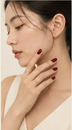 A model turned to the side, fingertips in deep burgundy